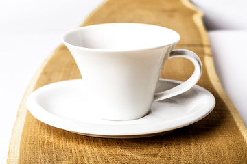 one pure white ceramic Cup and saucer stands on a wooden table