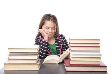 Adorable school girl reading a book at her desk