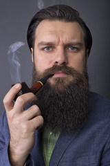Studio shot of a handsome young man with retro look smoking pipe