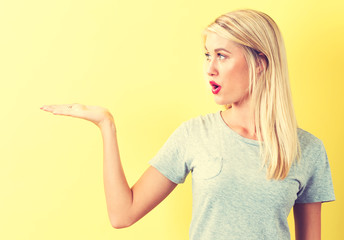 Young woman with a displaying hand gesture on a yellow background