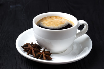 Black coffee with foam and anise on a black background