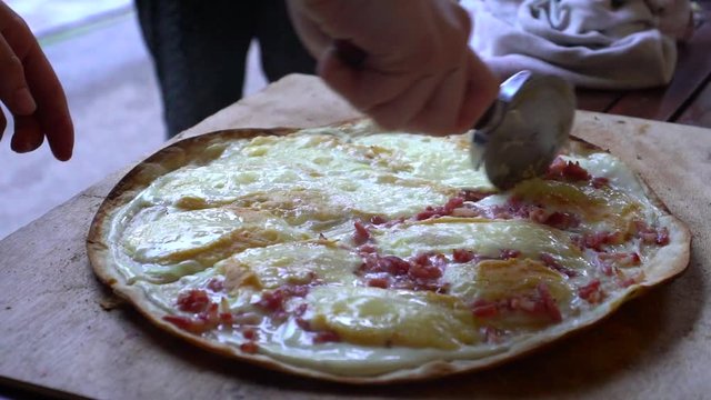 Cutting pizza slow motion view, alsacien special food, tarte flambe