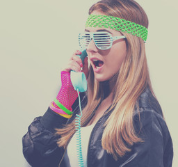 Woman in 1980's fashion with old fashioned phone on a white background