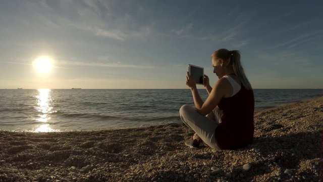 Young Woman Taking Pictures On The Beach Using Tablet