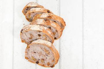 Slices of walnut bread on white wooden background
