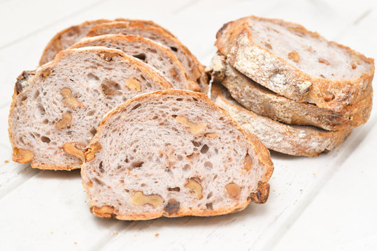 Slices of walnut bread on white wooden background