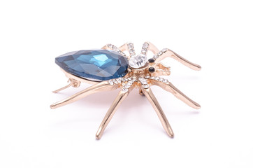 Golden spider with a big blue stone isolated on white
