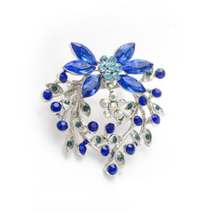 Silver flower brooch with blue diamonds isolated on white