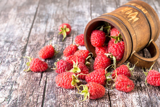  Raspberries.   Fresh ripe large raspberry berries in a brown wooden mug on an old table. The source of natural vitamins. Used in cooking and folk medicine.