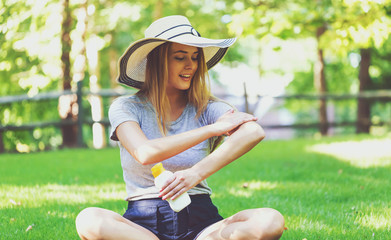 Young woman a bottle of sunblock outside on a summer day