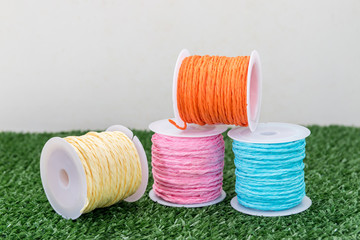 Four of colorful thread on grass with white background