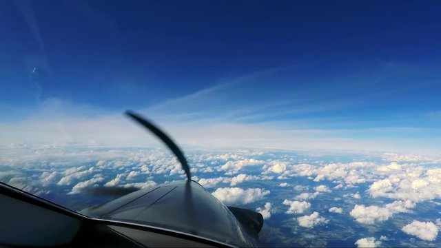 A private plane flies above the clouds - a view from the cockpit - spinning propeller