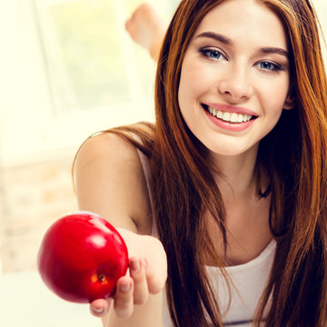 Smiling woman with red apple, indoors