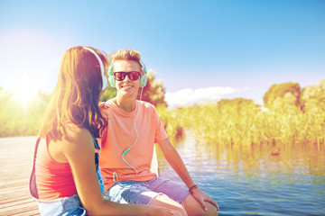 happy teenage couple with earphones on river berth