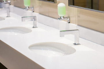 Water tap with soap press inside clean public restroom