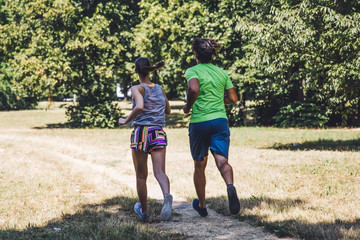 Fototapeta premium Young couple running in the park on a sunny day