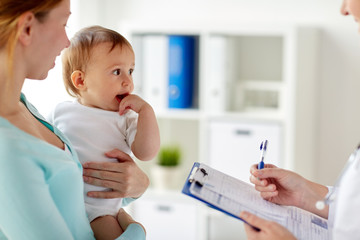 woman, baby and doctor with clipboard at clinic