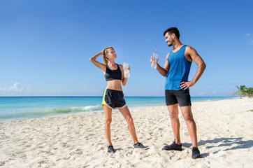 Runner couple drinking water at the beach