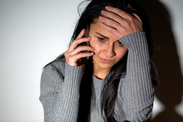 close up of crying woman calling on smartphone