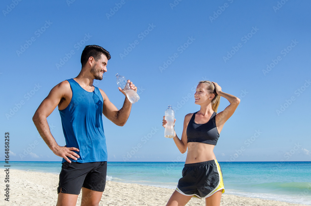 Wall mural fitness. couple drink water after training at the beach