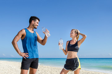 Fitness. Couple drink water after training at the beach