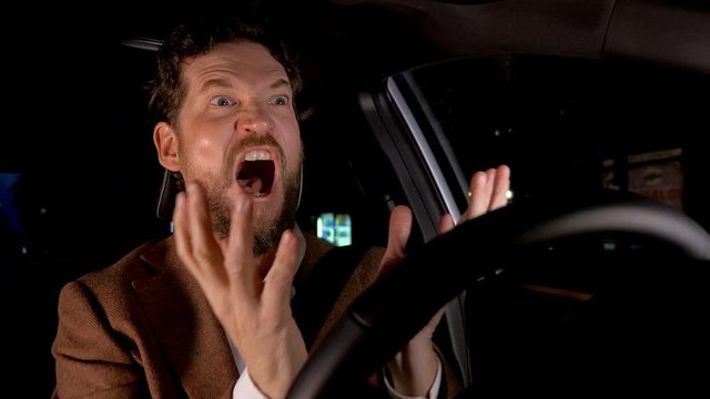 Man driving car at night screaming furious
