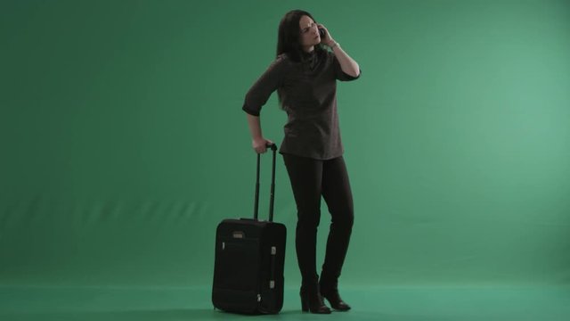 Young tired woman with a suitcase speaking on a phone