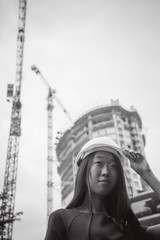Asian woman in a blue dress and white protective helmet. engineer supervises inspection and control of works at construction site.