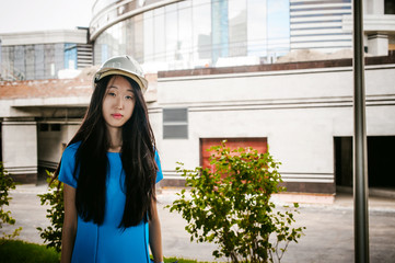 Asian woman in a blue dress and white protective helmet. engineer supervises inspection and control of works at construction site.