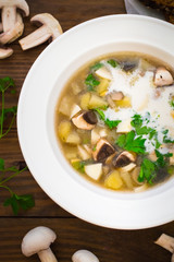 Delicious soup with wild mushrooms, potatoes, greens and cream. Wooden background. Top view. Close-up