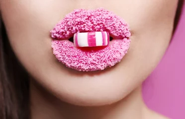 Schöne junge Frau, die Süßigkeiten in den mit Zucker bedeckten Lippen hält, Nahaufnahme © Africa Studio