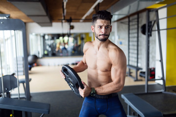 Fototapeta na wymiar Portrait of young strong man in gym