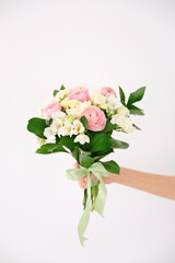 Female hand holding beautiful bouquet with freesia flowers on white background