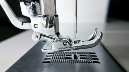 Close-up detail of the sewing machine  and needle textile phase of over stitching .