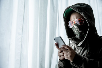 Hacker or terrorists  in hood with masked working on dark digital his on with cell telephone or...