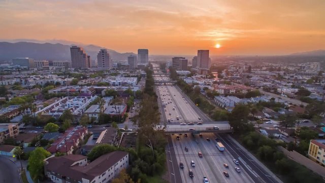 Aerial timelapse in motion (hyperlapse) shot at sunset in Los Angeles at twilight with the sky changing from day to night with stunning golden skies and the sun setting behind high rise buildings