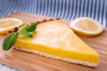 Piece of delicious lemon pie on wooden board, closeup