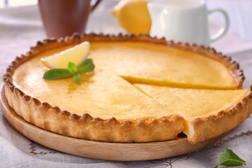 Wooden plate with delicious lemon pie on table, closeup