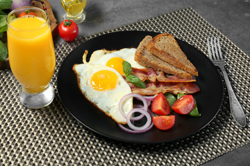 Delicious over easy eggs with vegetables and bacon on kitchen table