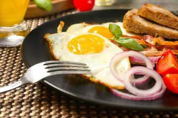 Delicious over easy eggs with vegetables and bacon on kitchen table