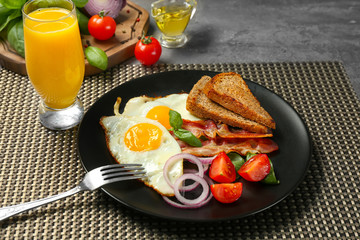 Delicious over easy eggs with vegetables and bacon on kitchen table