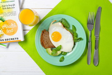 Delicious over easy egg with bread, avocado and basil leaves on kitchen table