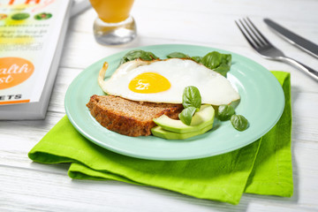 Delicious over easy egg with bread, avocado and basil leaves on kitchen table