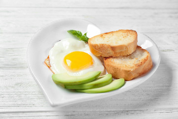 Delicious over easy egg with toasts and avocado on kitchen table