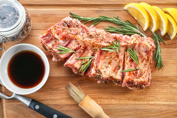 Raw pork ribs and ingredients for cooking on wooden board, closeup