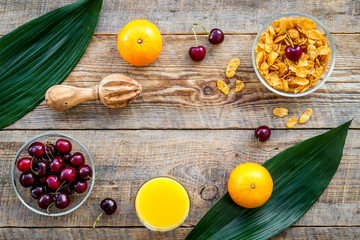 Summer fruity breakfast. Muesli, oranges, cherry on wooden table background top view copyspace