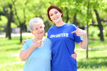 Young and senior woman pointing at t-shirt with text VOLUNTEER outdoors