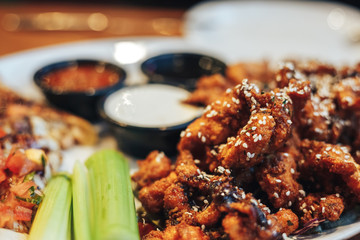 sliced chicken breast breaded and deep fried chicken pieces, sprinkled with sesame seeds, cream and tomato sauce , teriyaki sauce, celery root on a plate,slices of pizza with vegetables.