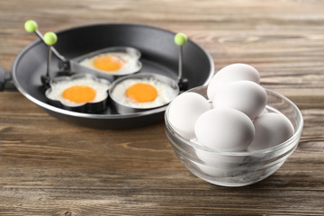 Composition with raw and sunny side up fried eggs on wooden table