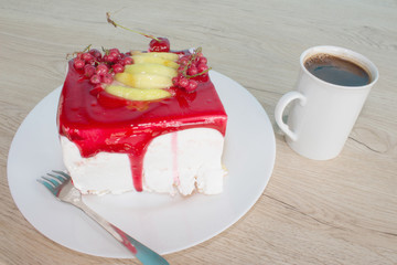A cup of coffee and cake on wooden background. Cake on white plate with fork